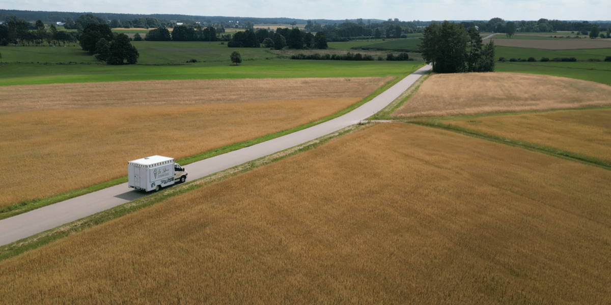 zdjęcia z drona w Białymstoku w ramach zlecenia reklamowego la storia - van jadący drogą pośród pól pełnych dojrzałych kłosów